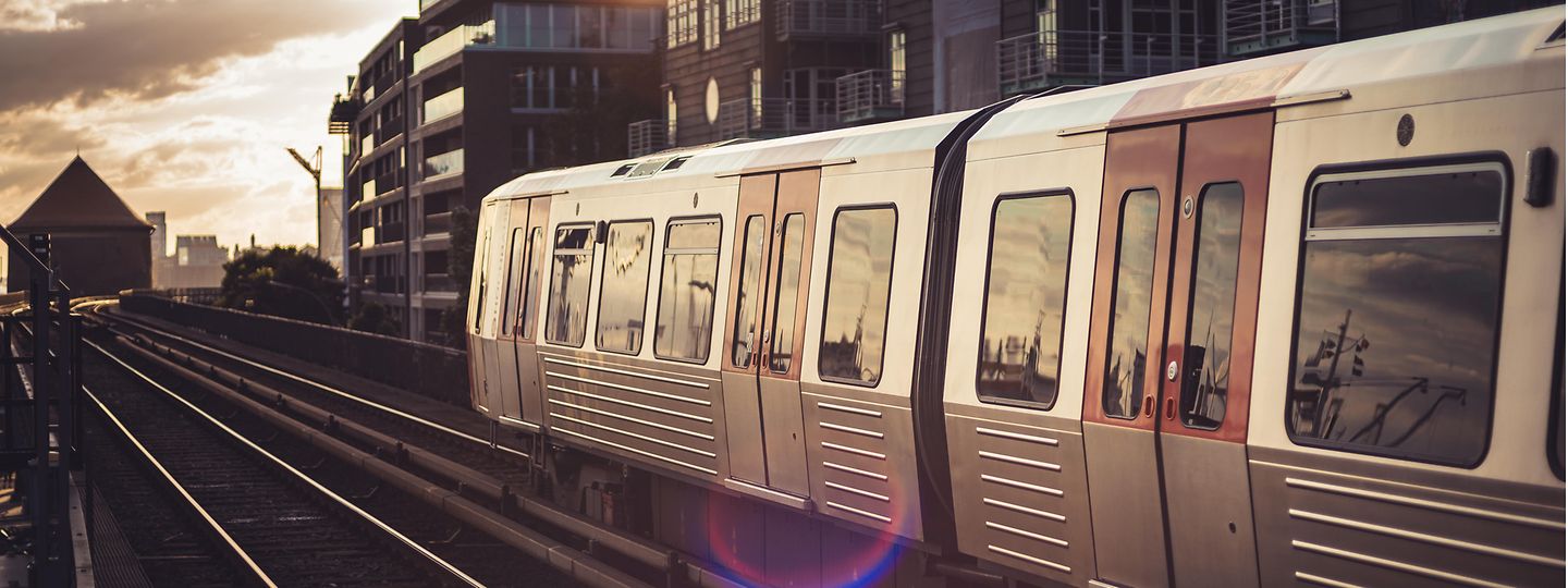 Die U-Bahn-Linie U3 der HOCHBAHN fährt im Abendlicht am Baumwall vorbei