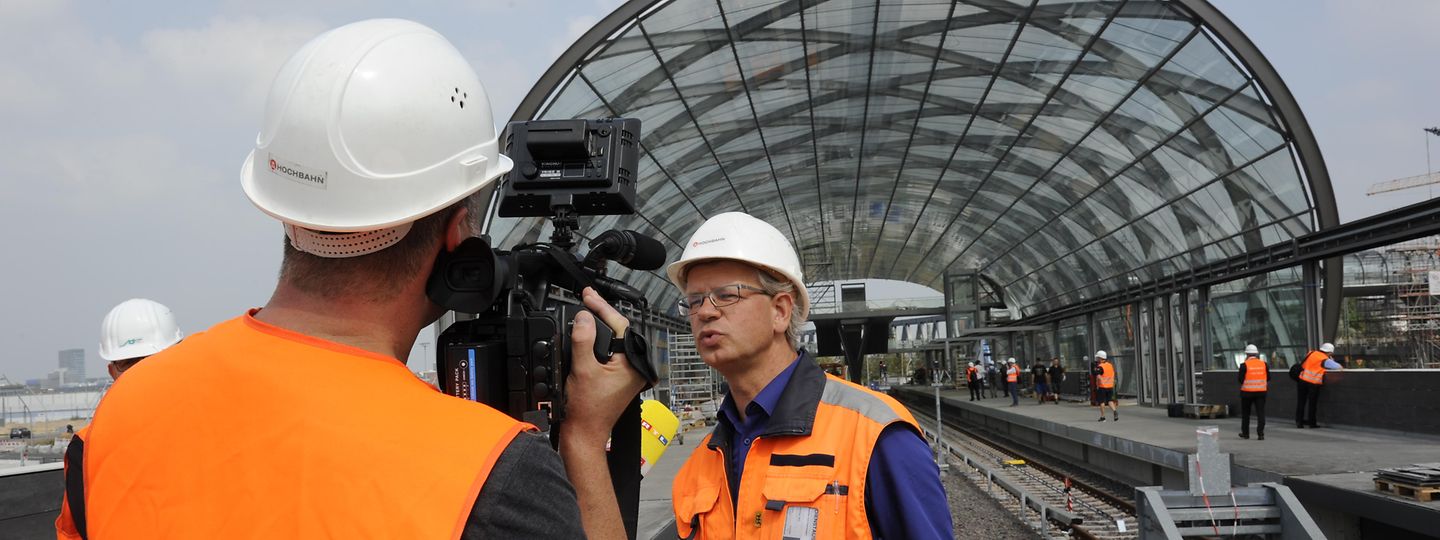 Ein Kamerateam interviewt einen Ingenieur der HOCHBAHN vor der U-Bahn-Haltestelle Elbbrücken
