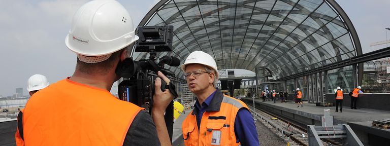 Ein Kamerateam interviewt einen Ingenieur der HOCHBAHN vor der U-Bahn-Haltestelle Elbbrücken